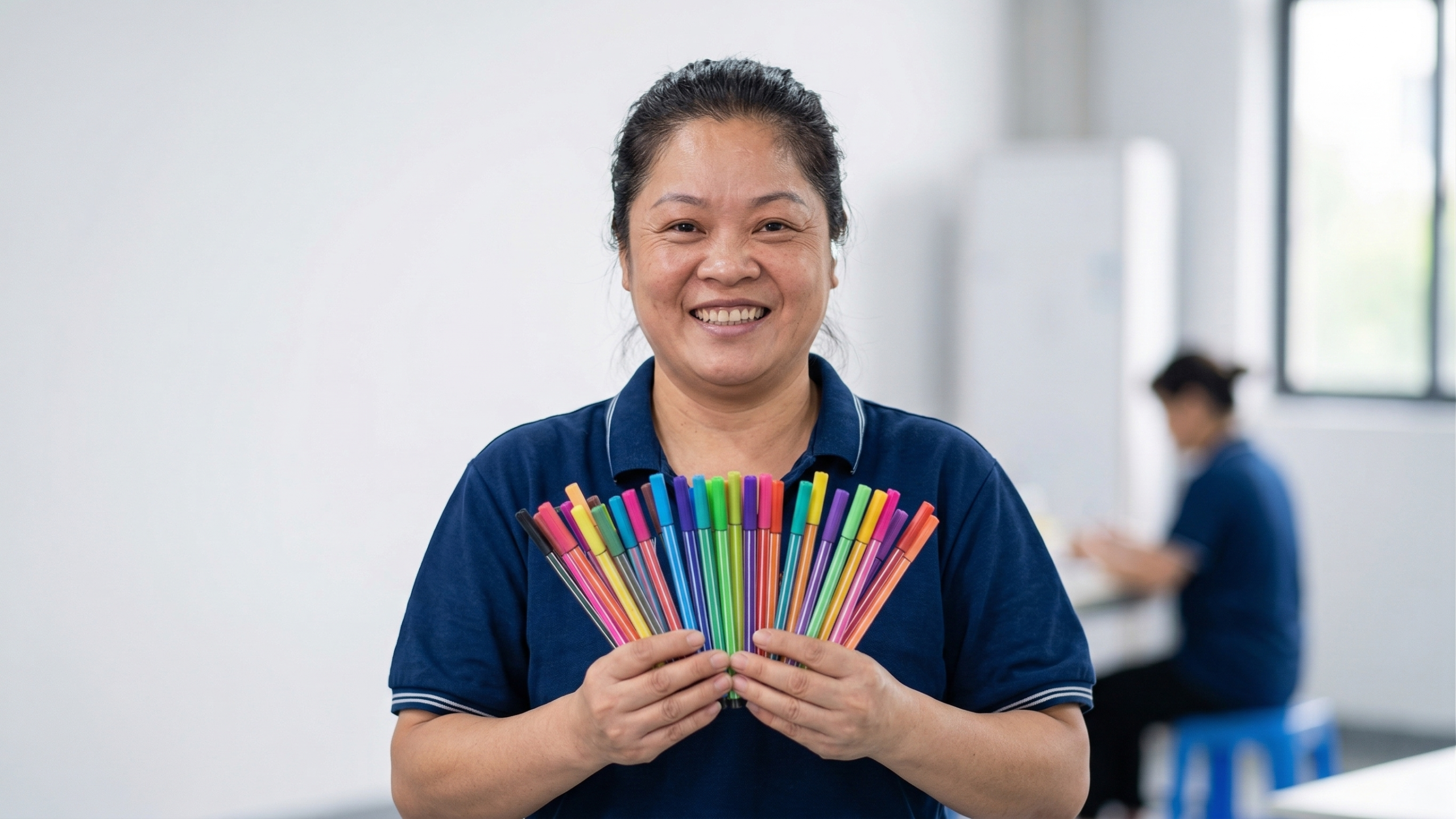 A group of smiling stationery factory workers in blue uniforms toasting during a team lunch, showcasing positive company culture.