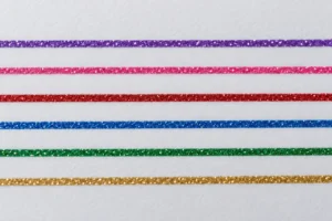 Separate purple, pink, red, blue, green and gold glitter ink lines on white paper